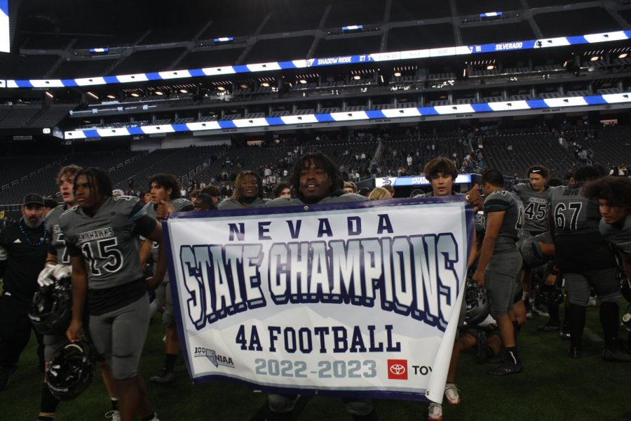 Martai Rutledge holds up State Champion banner on the Allegiant Stadium field on Nov. 21